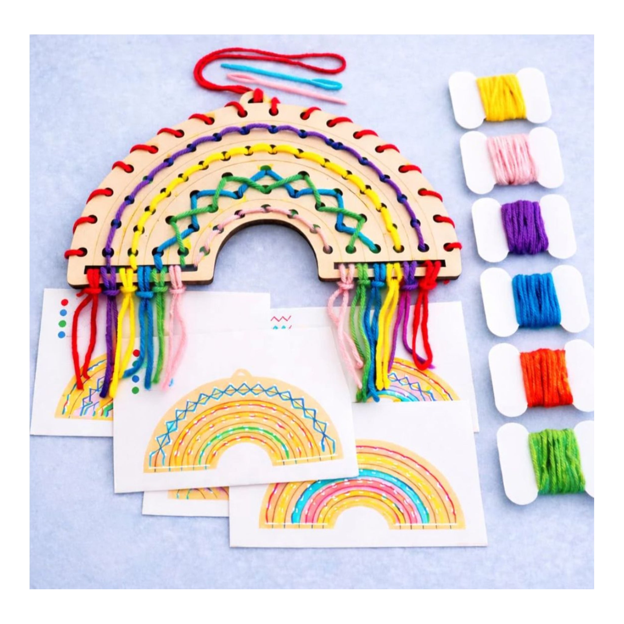 Wooden rainbow loom kit with colorful strings and spools on a light blue background